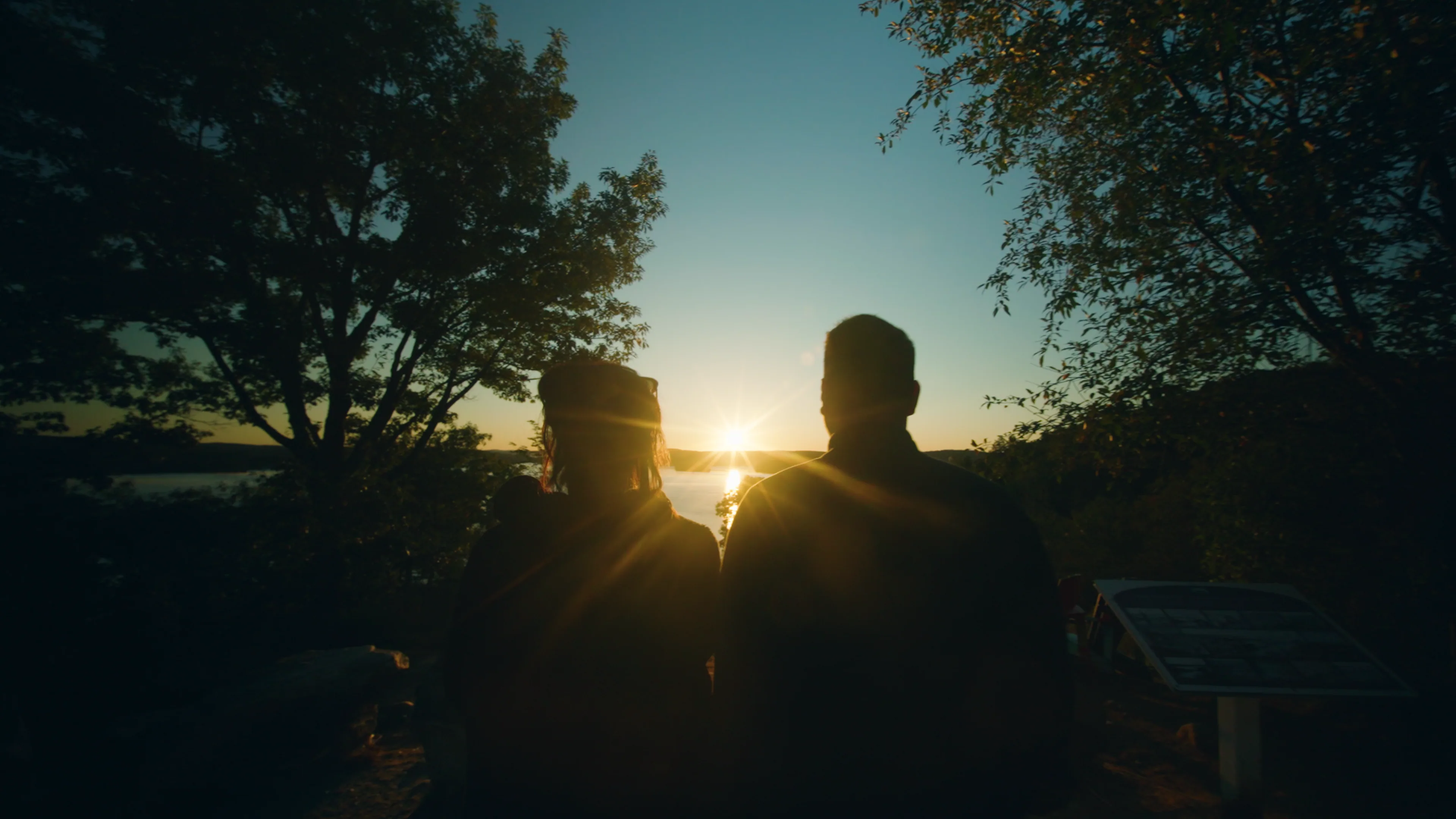 Two people looking out over the water at sunset.